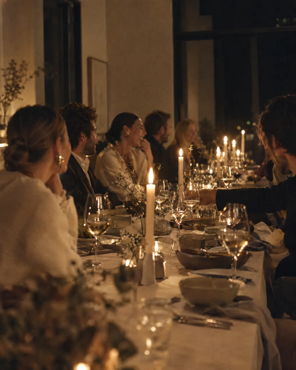 Langbord med levende lys og gjester i samtale